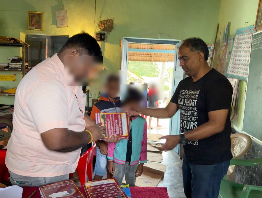 Richard handing notebooks to children at a Government school in Alur